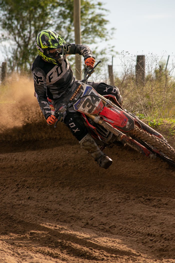 A Person Wearing a Black and White Racing Suit Riding a Motorcycle on Soil